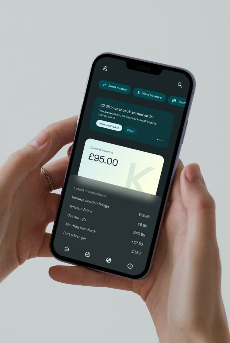 A person holds a smartphone displaying a finance app with a balance of £95.00 and recent transaction details on the screen.