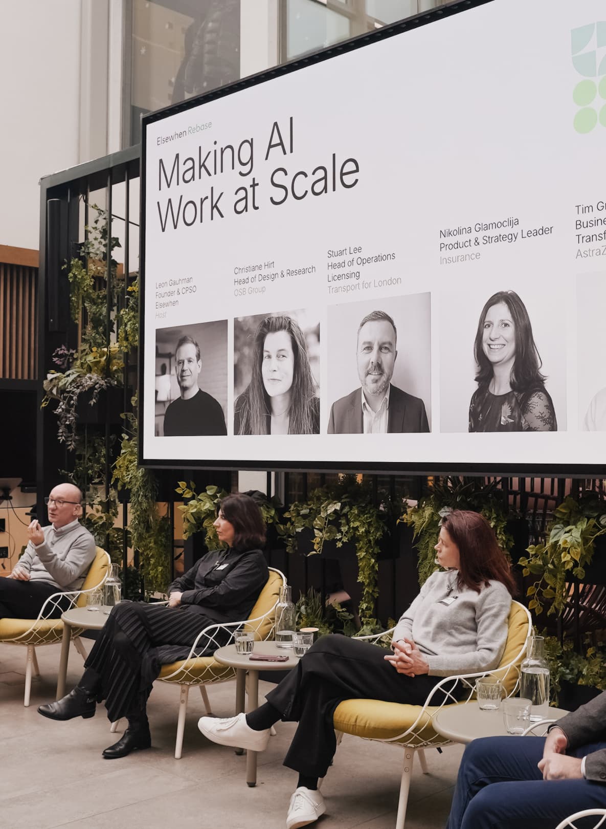 Panellists seated on stage at an Elsewhen Rebase event below a screen titled "Making AI Work at Scale" listing the five speakers