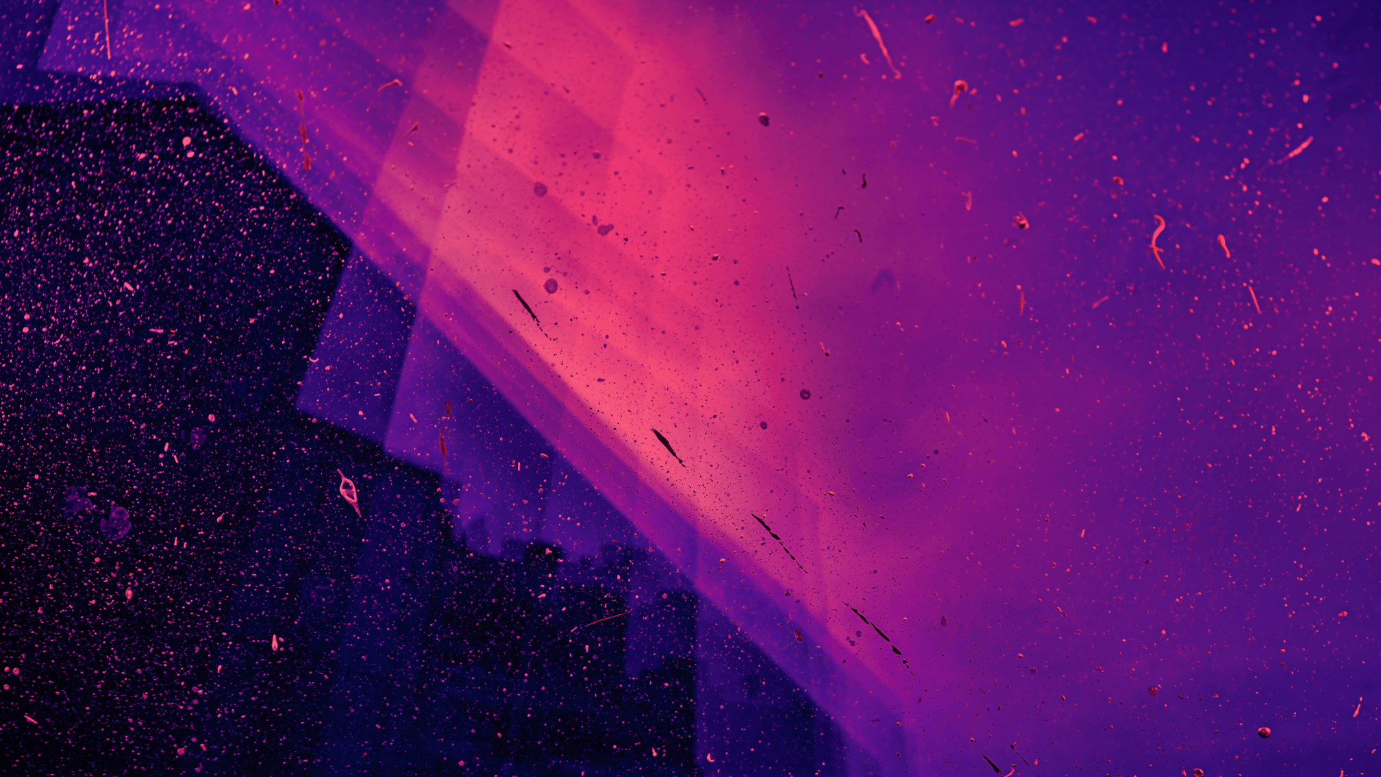 Vibrant abstract background with a purple to pink gradient, translucent geometric shapes, and scattered specks like dust or water.