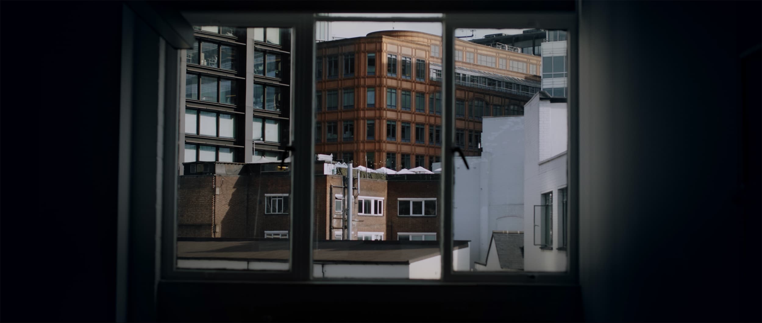 View through a window frame of brick and glass office buildings from a dark room