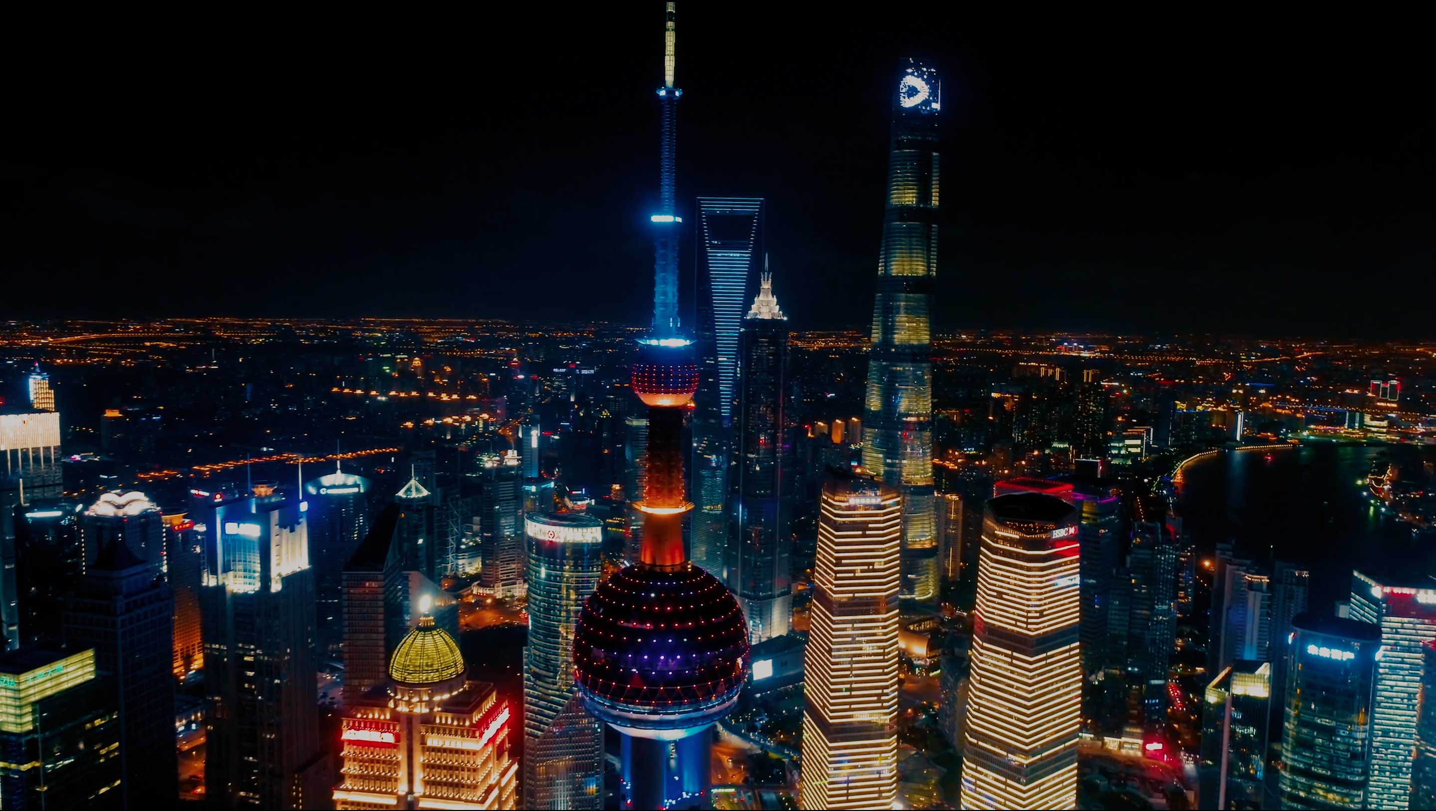 Shanghai skyline at night, featuring the illuminated Oriental Pearl TV Tower, Shanghai Tower, and other dazzling skyscrapers.