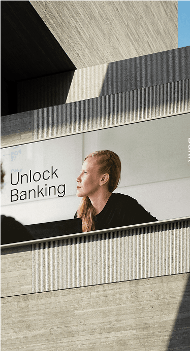 A large billboard on a modern building displays a picture of a person with long hair, accompanied by the text "Unlock Banking."