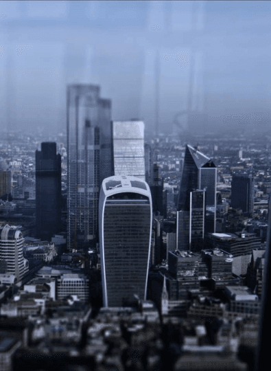Hazy city skyline of glass towers seen through a window, with a rounded top skyscraper in the centre