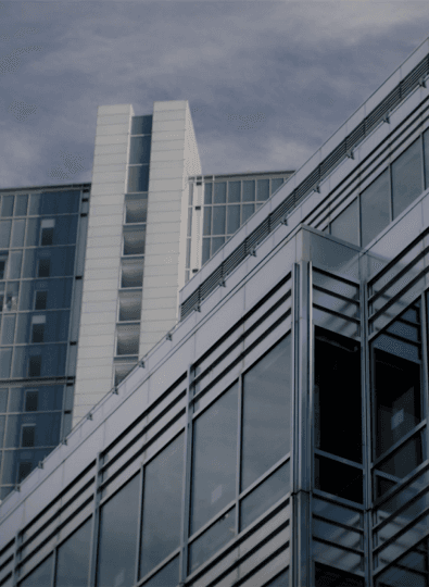 Modern office buildings with glass and white cladding against a cloudy blue sky